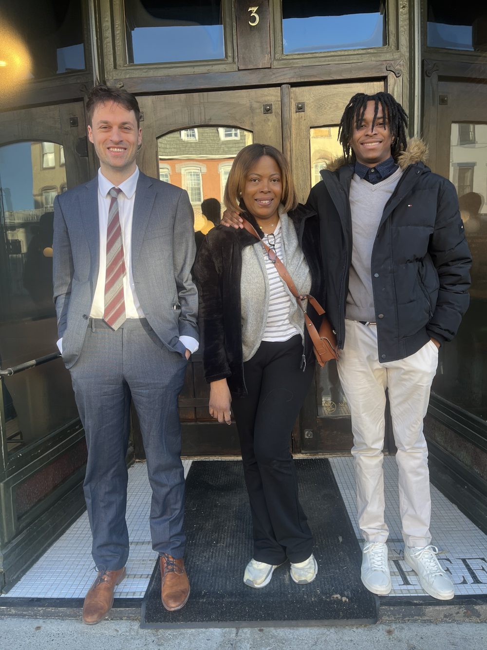 Thomas Plan with a client and the client's mother outside a building entrance.